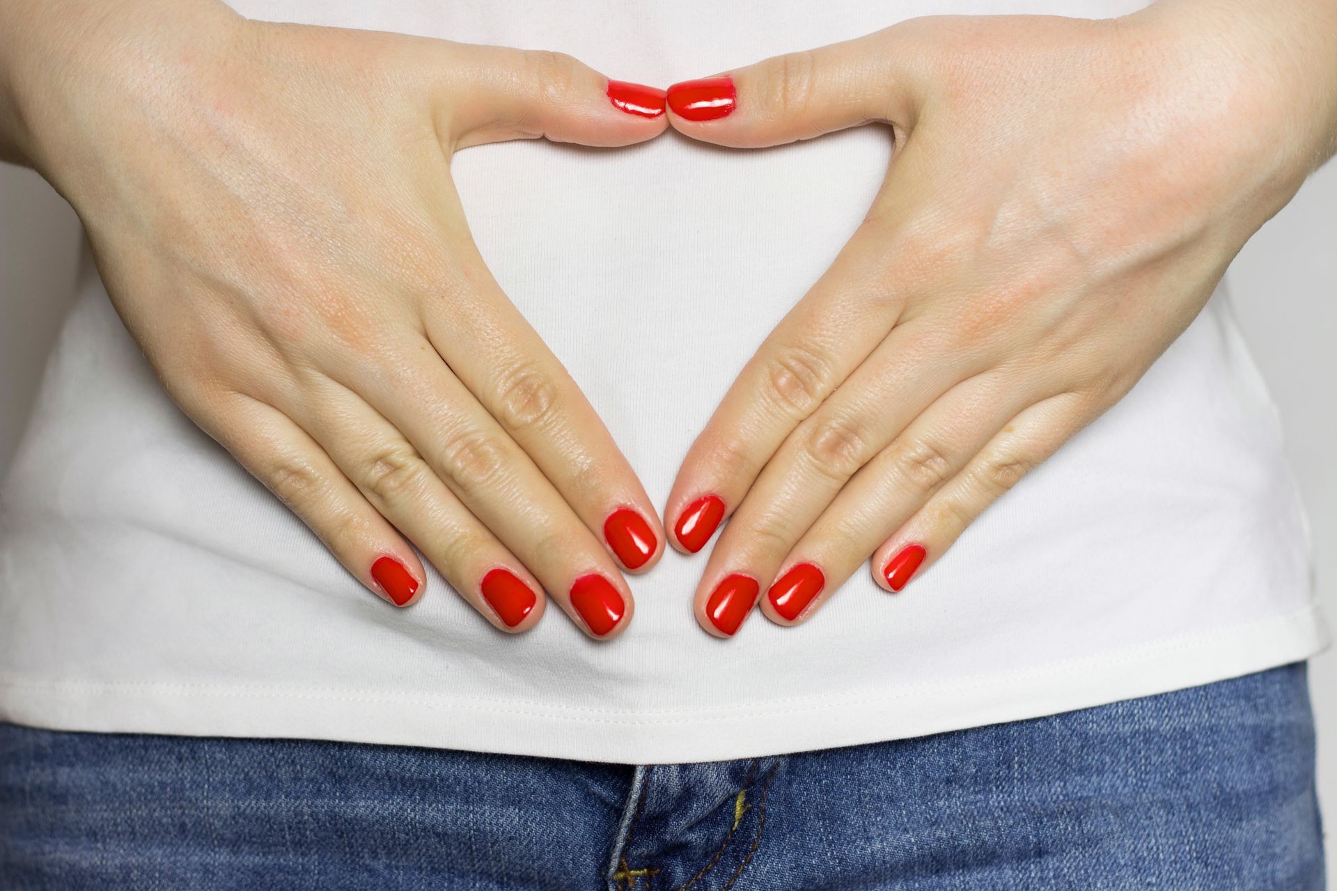 Female hands in the shape of a heart on the stomach. The concept of women's health